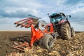 Farmer plowing stubble field with red tractor. Royalty Free Stock Photo