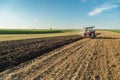 Farmer plowing stubble field with red tractor. Royalty Free Stock Photo