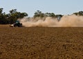 Farmer raises clouds of dust as he ploughs his dry Royalty Free Stock Photo