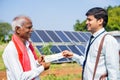 Farmer receiving bank check from banker in front of solar lenal at farmland - concept of finacial, agricultural loan and Royalty Free Stock Photo