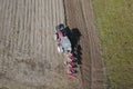 A farmer on a red tractor with a seeder sows grain in plowed land in a private field in the village area. Mechanization of spring