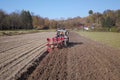 A farmer on a red tractor with a seeder sows grain in plowed land in a private field in the village area. Mechanization of spring Royalty Free Stock Photo