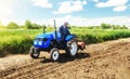 A farmer rides across the field on a tractor with a milling machine. Loosening surface, cultivating land for planting. Farming and