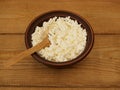 Farmer's cottage cheese with a wooden spoon in a handmade earthenware bowl on a wooden background. Healthy dietary Royalty Free Stock Photo