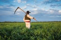 Farmer with a scythe on green field