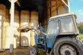 Farmer seen in his tractor loading bales in a straw shed. Royalty Free Stock Photo