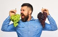 Farmer shows his harvest. Winegrower with wild face holds grapes