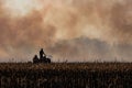 Farmer silhouette fighting fire in agricultural farming field with wall of smoke