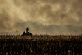 Farmer silhouette fighting fire in agricultural farming field with wall of smoke