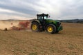 A farmer working on the field with a John Deere tractor