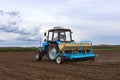 A farmer with a sowing tractor - sowing crops on an agricultural field. Plants, wheat.