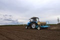 A farmer with a sowing tractor - sowing crops on an agricultural field. Plants, wheat.