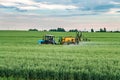 Farmer spraying wheat field with tractor sprayer at spring season