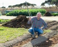 Farmer spreads rake garden beds