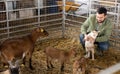 Farmer squatting with goatling in shed