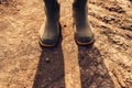 Farmer standing on dirt country road, close up of boots