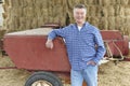 Farmer Standing In Front Of Bales And Old Farm Equipment Royalty Free Stock Photo