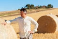 Farmer standing near bale of wheat. Harvestimg in Tuscany, Italy. Stacks of hay on summer field. Hay and straw bales in the end of Royalty Free Stock Photo