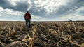 Farmer standing in a plowed field under a cloudy sky. Concept of agriculture and rural life. Background of a lone farmer Royalty Free Stock Photo