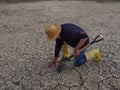 farmer with a straw hat kneeling on the dry, cracked ground. Arid terrain Royalty Free Stock Photo