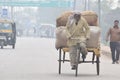 A farmer takes a cycle rickshaw in a city street