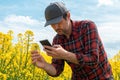 Farmer taking photograph of blooming rapeseed crop with mobile smart phone