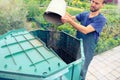 Farmer throws weeds and organic waste from his garden into compost heap. Composting - eco friendly recycling technology. Organic