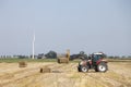 Farmer in tractor busy collecting hay bales with tractor in dutch province of groningen