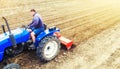 A farmer on a tractor cultivates a farm field. Field land preparation for new crop planting. Grinding and loosening soil, removing Royalty Free Stock Photo