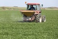 Farmer in tractor fertilizing wheat field