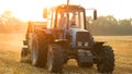 Farmer on tractor harvesting field at the evening.