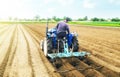 Farmer on a tractor making ridges and mounds rows on a farm field. Preparing the land for planting future crop plants. Cultivation