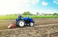 Farmer on a tractor with milling machine loosens, grinds and mixes soil. Field preparation for new crop planting. Loosening