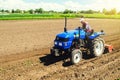 Farmer on a tractor with a milling machine processes loosens soil in the farm field. Grind and mix soil on plantation. Preparation