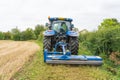 Farmer in a tractor mowing a grass verge on the edge of a field. UK