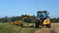 Farmer in a tractor mowing a grass verge with a flail. UK