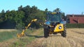 Farmer in a tractor mowing a grass verge with a flail. UK