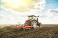 Farmer in tractor preparing land with seedbed cultivator.