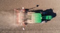 Farmer with tractor with seeder, sowing seeding crops at agricultural field. Top view.