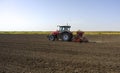 Farmer with tractor seeding crops at field