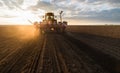 Farmer with tractor seeding - sowing crops at agricultural field