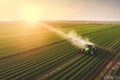 Farmer on a tractor spraying soybean field at sunset. Tractor drives through a green field and sprays crops. Generative AI Royalty Free Stock Photo