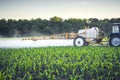 farmer on a tractor with a trailed sprayer makes fertilizer for young corn in the form of microdroplets