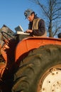 Farmer on tractor working on laptop computer