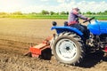 A farmer on a tractor works the field with a shredder in preparation for planting a new crop. Loosens, grind and mix soil.