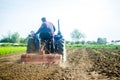 A farmer on a tractor works the soil of a farm field. Loosening surface, land cultivation. Farming, agriculture. Use of