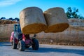 Farmer unloading round bales of straw with a front end loader