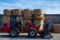 Farmer unloading round bales of straw with a front end loader