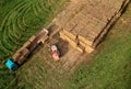 Farmer unloading round bales of straw from Hay Trailer with a front end loader. Store hay at farm. Hay rolls as Forage feed for