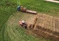 Farmer unloading round bales of straw from Hay Trailer with a front end loader. Store hay at farm. Hay rolls as Forage feed for Royalty Free Stock Photo